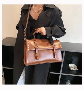 Detail of vintage brown leather satchel with metal ring buckle and rivet accents