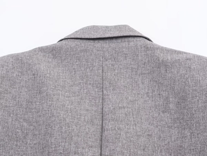 Close-up of herringbone texture and shoulder stitching on a grey blazer set