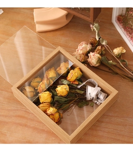 Detail of wooden shadow box frame with preserved yellow roses and transparent glass panels