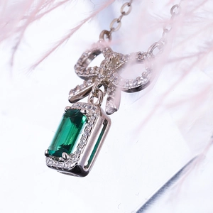 Elegant S925 silver necklace with emerald cut green gemstone and bow-shaped pendant detail