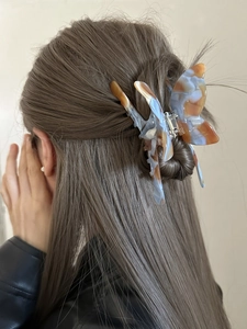 Detail of a large butterfly hair claw clip with blue and brown marble texture on a model
