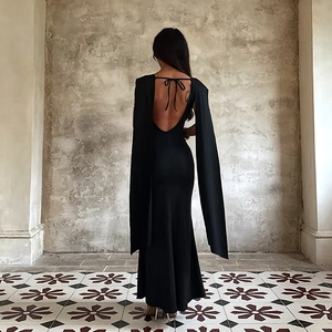 Detail of elegant black backless evening dress featuring dramatic cape sleeves and slim fit