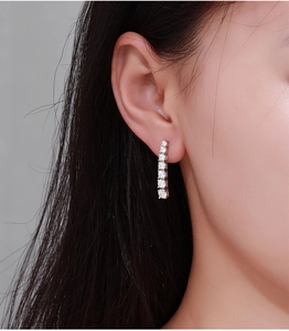 Close-up of elegant silver moissanite tassel earring worn on model's ear lobe
