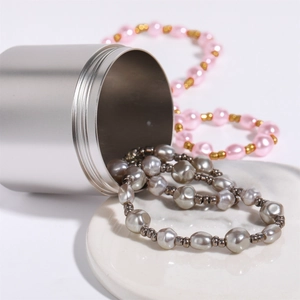 Baroque pearl necklaces in grey and pink styles displayed with a silver metal container