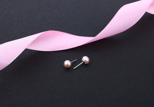 Close-up of pink freshwater pearl earrings on black textured background with silk ribbon