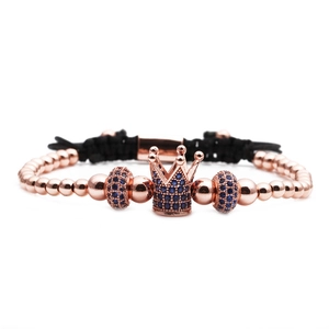 Detail of rose gold crown bead with blue zircon on black woven adjustable bracelet
