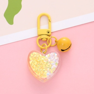 Close-up of yellow heart keychain with glitter stars and matching bell charm