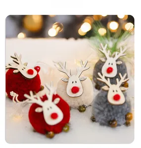 Detailed close-up of felt reindeer ornaments in red, white and grey on snowy background
