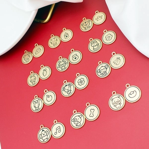 Golden zodiac metal charms with cartoon animal engravings on dark red background