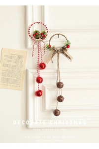 Detail of Christmas wreath ornaments with pine needles, red berries and festive bells