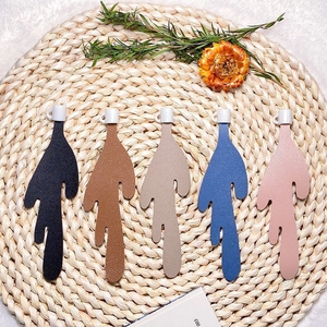 Detailed view of leaf-shaped leather bookmarks in five colors on a woven mat