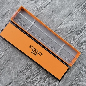 Detailed view of an orange and black rectangular gift box with SHIRLEY BEE logo brand