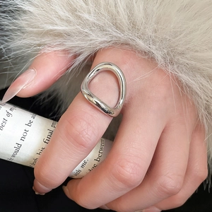 Close-up of a silver irregular liquid metal ring worn on index finger with trendy design