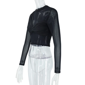 Detail of sheer mesh patchwork and twist knot design on a black long sleeve crop top