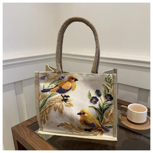 Detailed close-up of bird and floral embroidery on a linen cotton tote bag