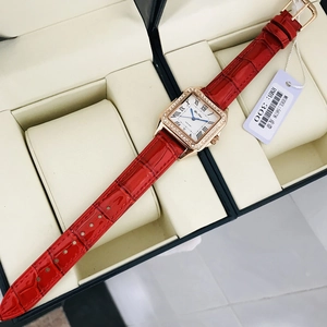 Detailed view of square gold watch with crystal bezel and red crocodile leather strap