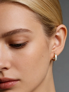 Close-up of brushed silver and gold two-tone square hoop earrings on a model