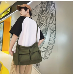 Model wearing army green canvas messenger bag with multiple pockets and wide strap