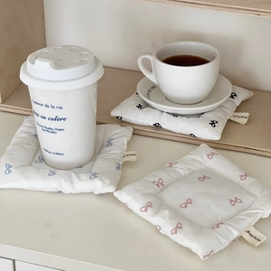 Close-up of quilted bow print coasters with Jump for Joy label on a wooden shelf