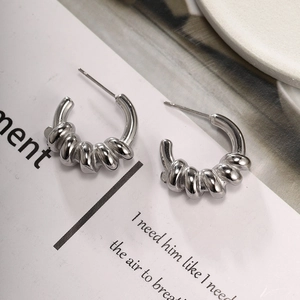 Detailed macro view of silver C-shape twisted hoops with textured surface on a white card