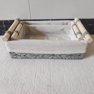 Detail of woven storage basket with off-white fabric liner and light wood handles