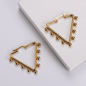 Detail of gold geometric triangle hoop earrings with small beads on a white pedestal