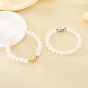 Vue détaillée de bracelets en perles blanches avec fermoirs dorés et argentés sur soie