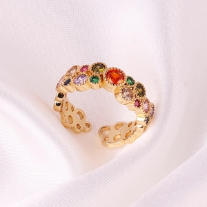 Detail view of colorful gemstones and hollow pattern on gold adjustable ring