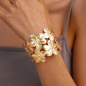 Detailed macro view of gold flower cuff bracelet with layered metallic petals and brushed texture
