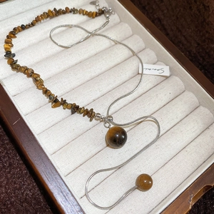 Detail of tiger eye stone bead and silver snake chain necklace on a wood jewelry box