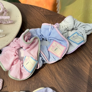 Detail of fabric scrunchies in pink, blue, and grey with NOTES label on wood