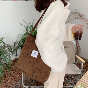 Brown corduroy tote bag with cute bear pattern worn by a model in outdoor setting