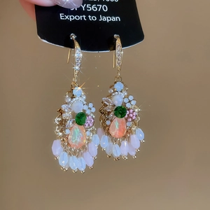Detail of bohemian drop earrings with green faceted stones and colorful tassel beads