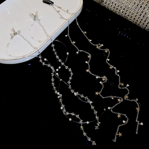 Détail d'une pince à cheveux papillon argentée avec glands de perles et chaînes d'étoiles