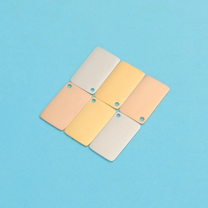Gros plan de pendentifs enveloppes en métal doré, argenté et or rose de forme rectangulaire