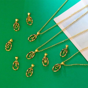 Detailed macro view of gold letter pendants with colorful zircon inlay on green background