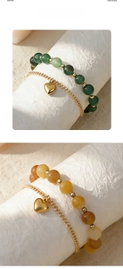 Detail of layered couple bracelets with green beads and golden heart charms on textured roll