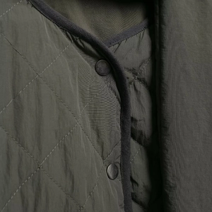 Women's olive green quilted jacket with diamond patterns and round metal snap buttons