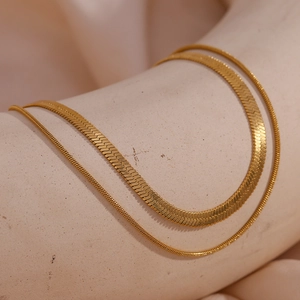 Detail of layered gold double strand bracelet with flat snake chain and slim round link
