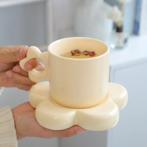 Ceramic mug with chunky wave handle and flower saucer in creamy yellow spotted glaze