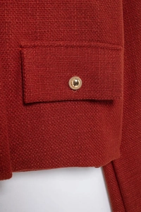 Détail d'une veste en tweed rouge avec maille haute densité et boutons dorés gaufrés