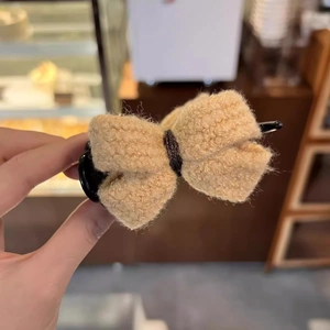 Detailed view of beige plush bow hair claw clip featuring wool texture and black plastic base