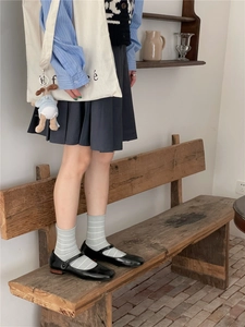 Classic black patent leather Mary Jane shoes with grey striped crew socks on a model