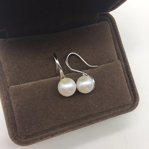 Macro view of freshwater pearl earrings with silver hooks in a velvet gift box