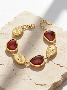 Detail of 18K gold plated bracelet with reddish-brown resin inlays on stone surface