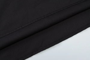 Nahaufnahme der schwarzen Stofftextur mit detaillierten Nähten und weichen Kleiderfalten