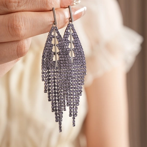 Macro detail of long purple rhinestone tassel earrings with silver geometric accents