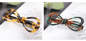 Detailed view of tortoiseshell pattern acetate bow hair clips in amber and dark green