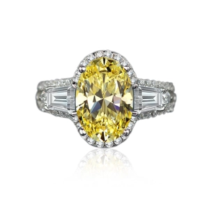Detail van ovale gele edelsteen ring met diamanthalo en trapezevormige zijstenen
