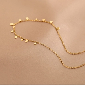 Detailed close-up of golden teardrop pendant necklace on elegant beige silk fabric